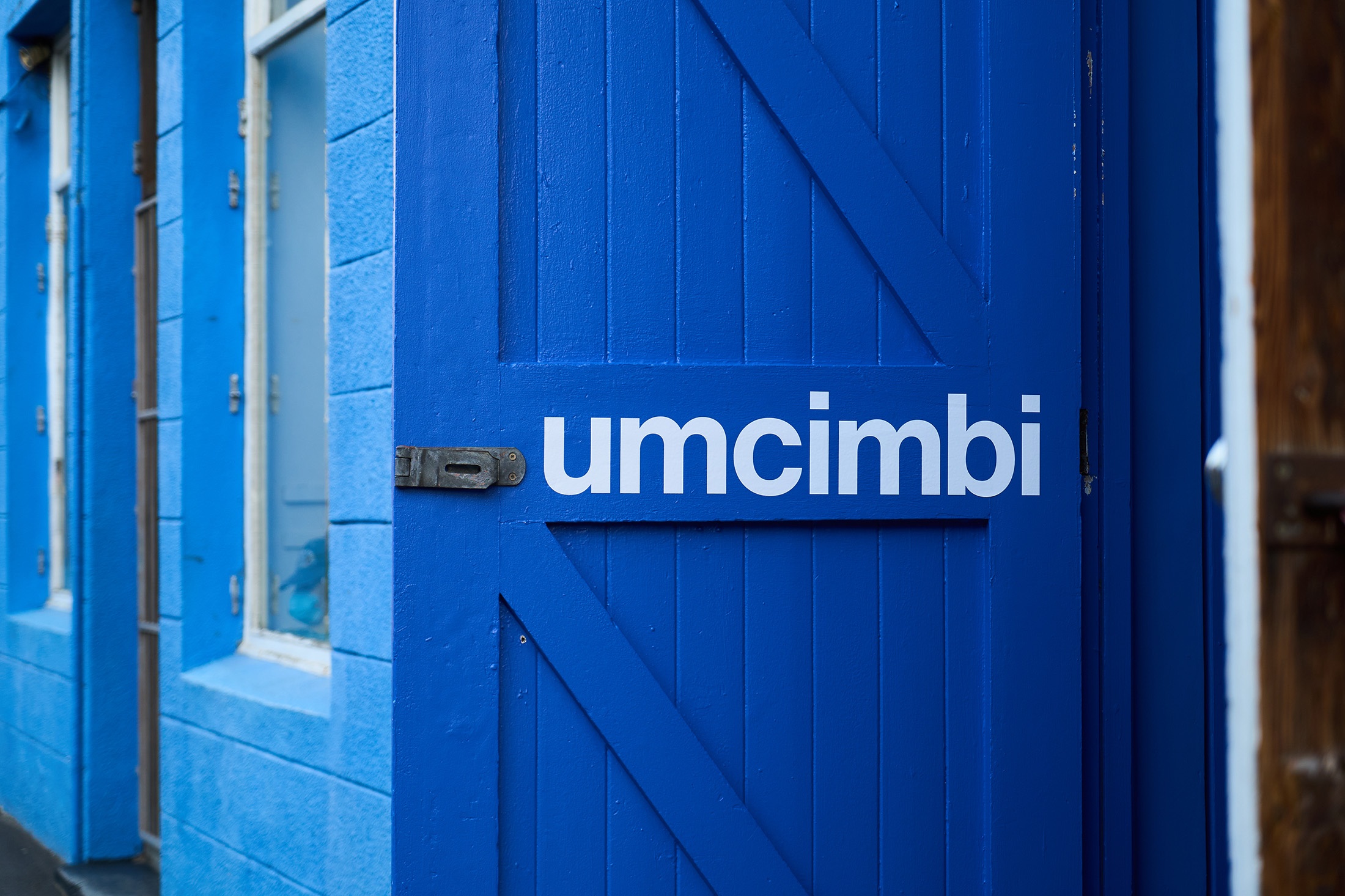 Event photograph from the ‘Umcimbi’ exchange with advocacy organisation ‘Back 2 School’ hosted in A4’s Goods project space. The white event title lines the inside of the blue project space door.
