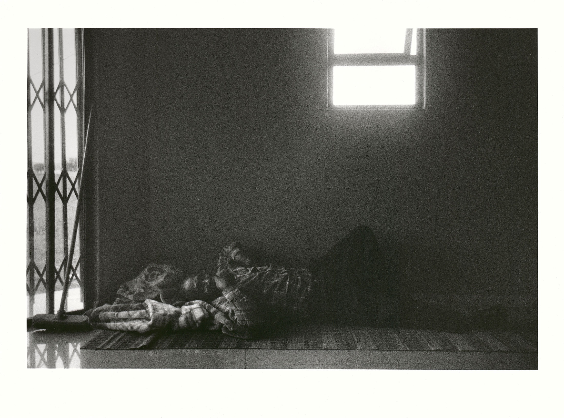 Sabelo Mlangeni’s ‘Umkhongi, the chief negotiator’ – a black and white photograph depicting a negotiator for a wedding lying on a mat indoors.
