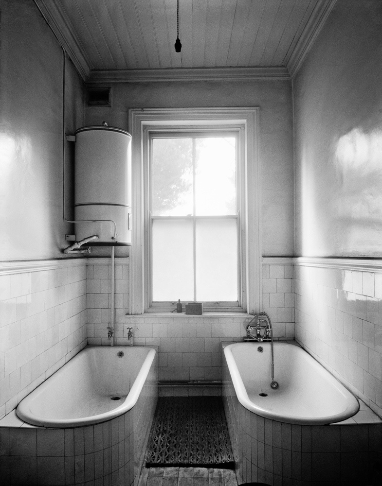 David Goldblatt's monochrome photograph "Bathroom attached to the office of the General Manager with ‘dirty’ bath and ‘clean’ bath for his use after he had been underground. New Kleinfontein Gold Mine, Benoni, May 1967".
