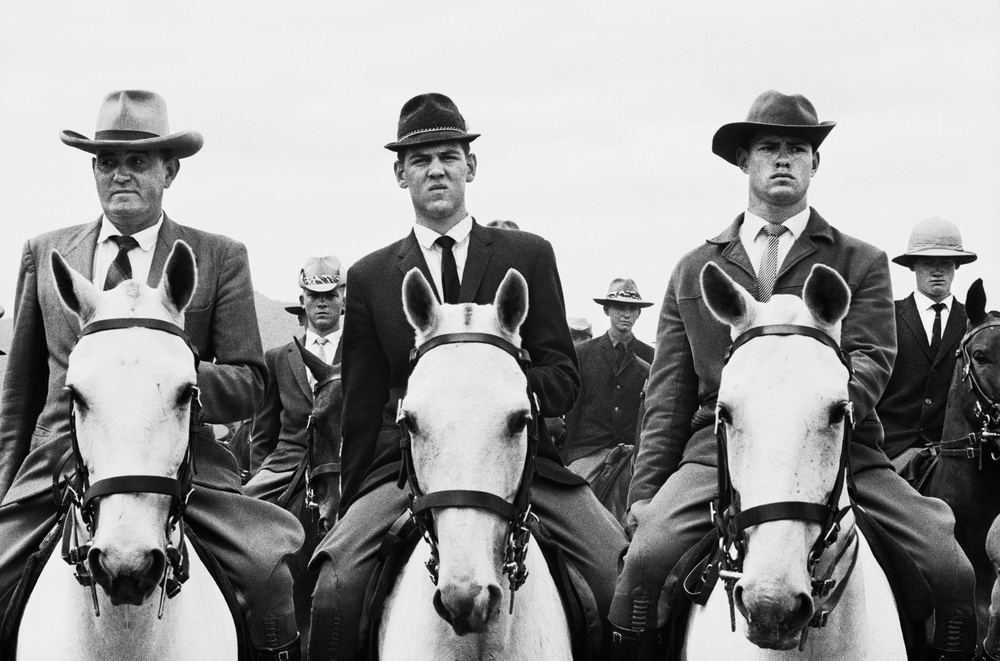 David Goldblatt's monochrome photograph 'The commando of National Party stalwarts which escorted prime minister and National Party leader Hendrik Verwoerd and his wife Betsie to the party’s 50th anniversary celebrations at de Wildt, Transvaal' shows multiple individuals seated on horseback.
