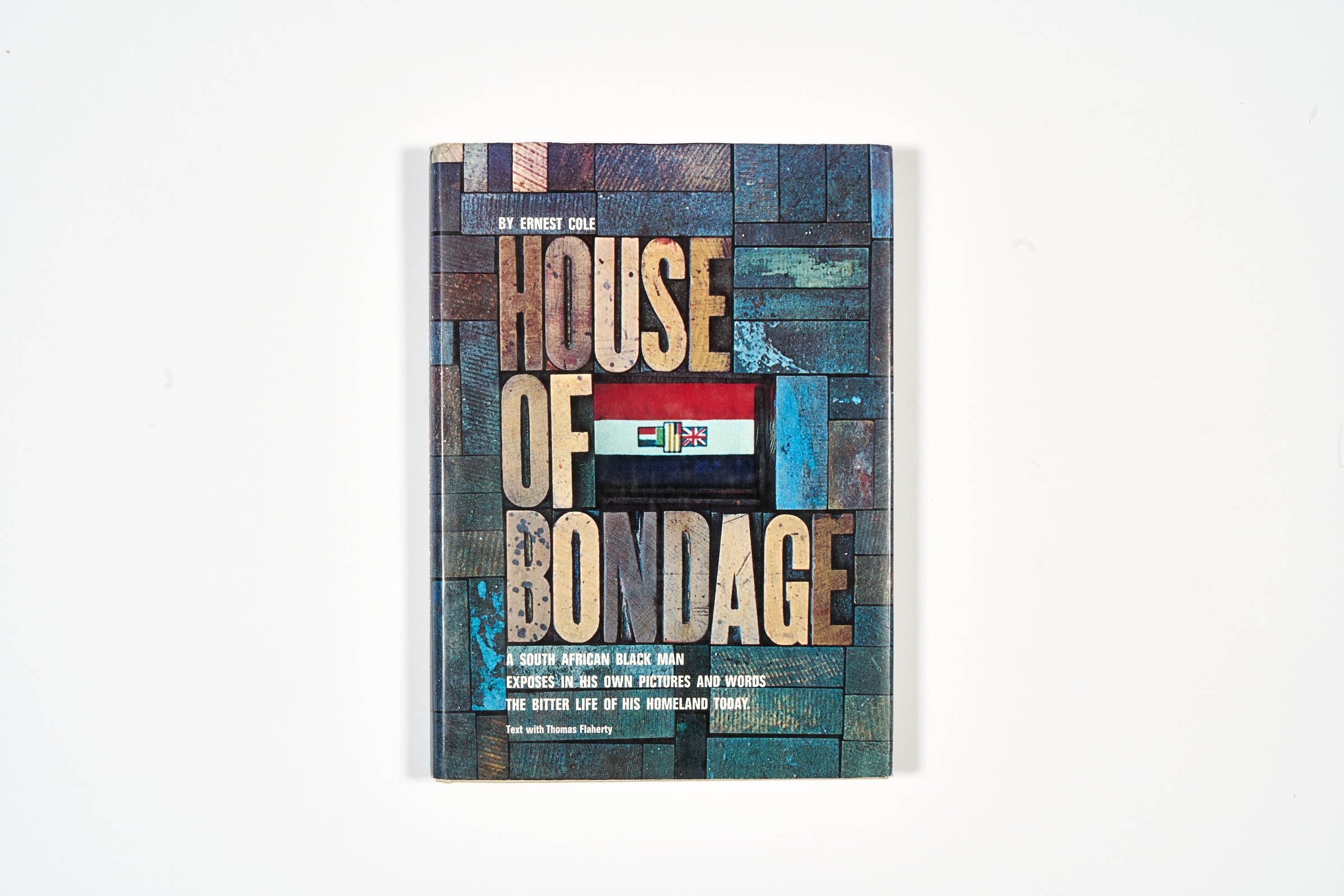 A topdown photograph of the cover of Ernest Cole's photo-book 'House of Bondage' on a white background.
