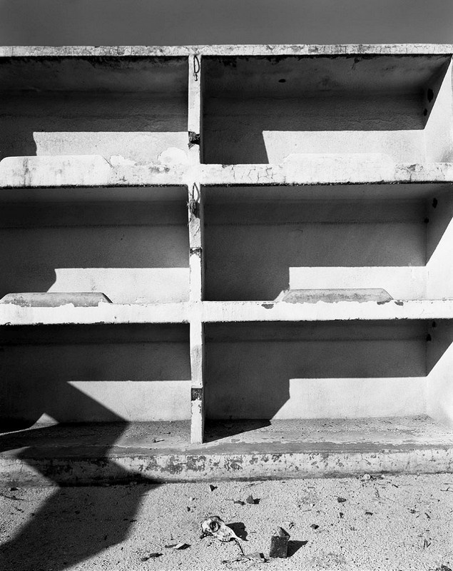 David Goldblatt's monochrome photograph 'Miners’ bunks in the abandoned Chinese compound, so called because it probably housed indentured Chinese labourers between 1904 and 1910, after which it accommodated black miners. Simmer & Jack Gold Mine, Germiston, July 1965' shows three rows of miners' bunks.
