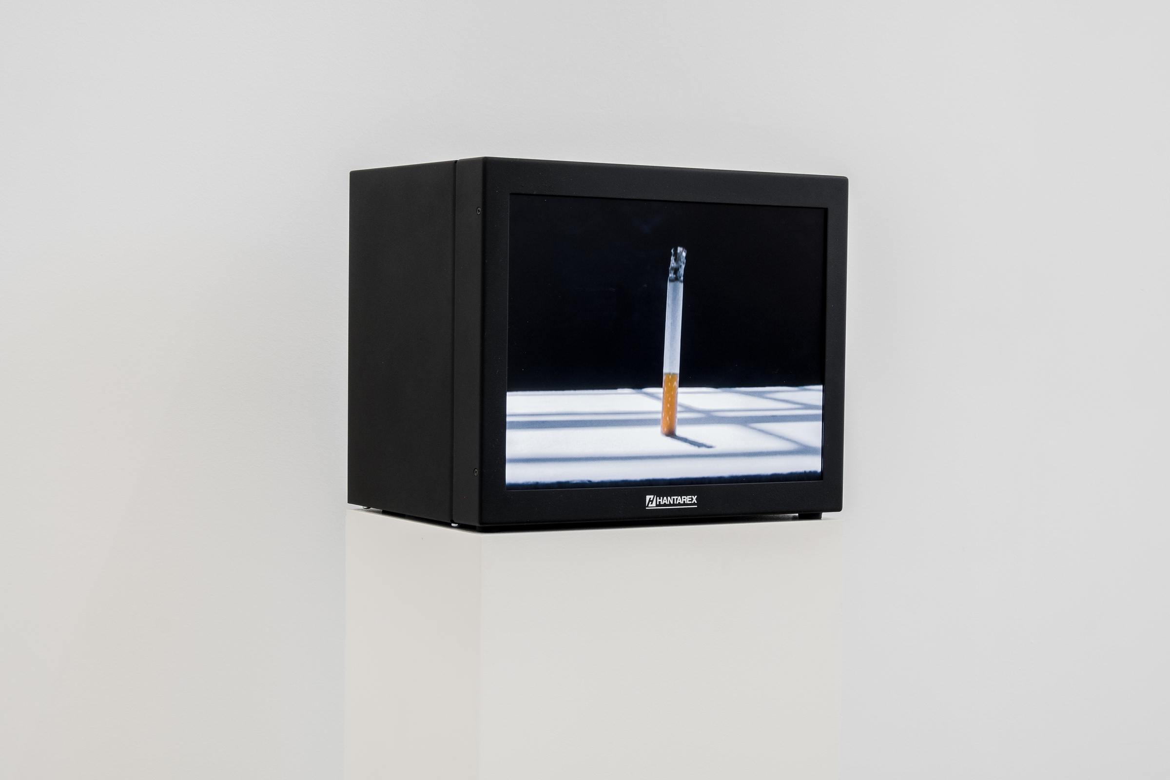 A photograph of Kemang Wa Lehulere's video work 'Lefu La Ntate' playing on a television screen sitting on a white plinth.
