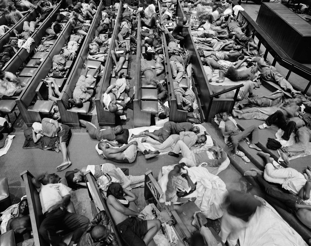 David Goldblatt's black-and-white photograph 'Zimbabwe refugees given shelter in the Central Methodist Church, Johannesburg' shows people sleeping in between multiple church pews.
