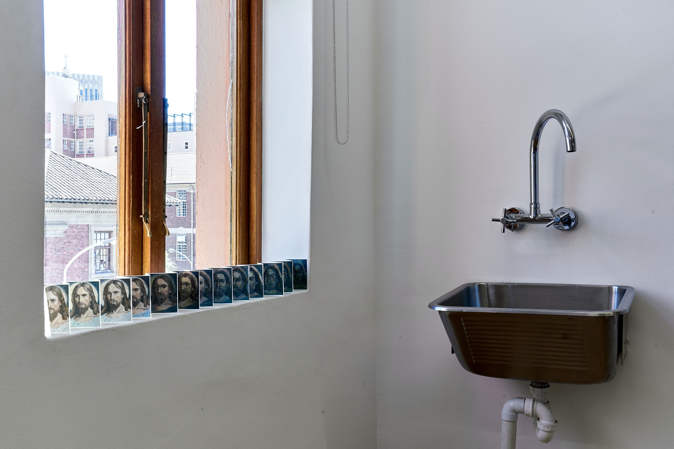 Process photograph from Patrick Waterhouse's 2022 residency in A4 Arts Foundation's studio. On the left, a windowsill holds a small paper accordion with photographic prints.
