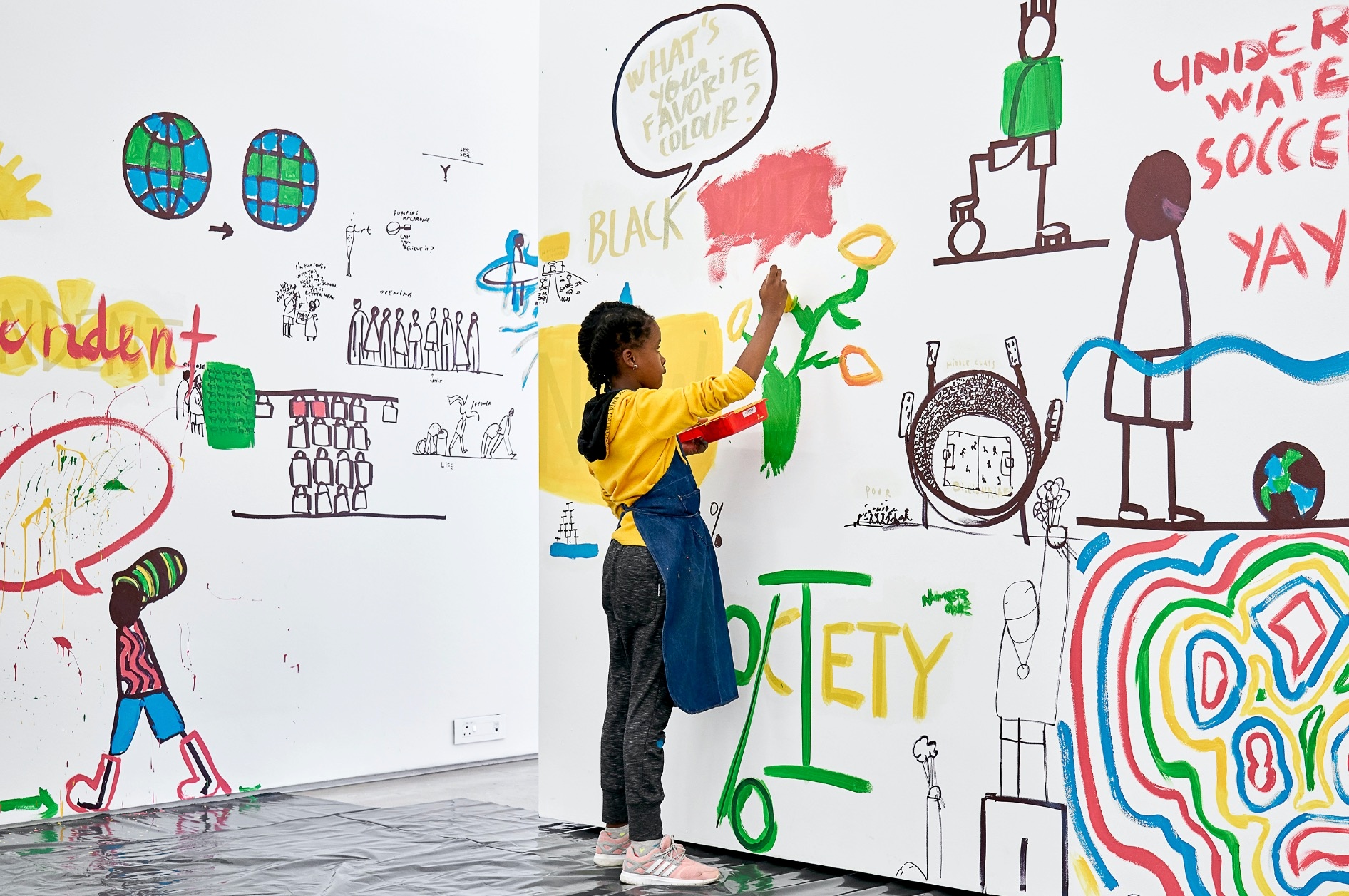Photograph from the ‘Colourful Erasure’ event in A4’s Gallery. On the right, a young participant paints in colour onto the gallery walls, “erasing” the black and white drawings from Dan Perjovschi's ‘Black & White Cape Town Report’ exhibition.

