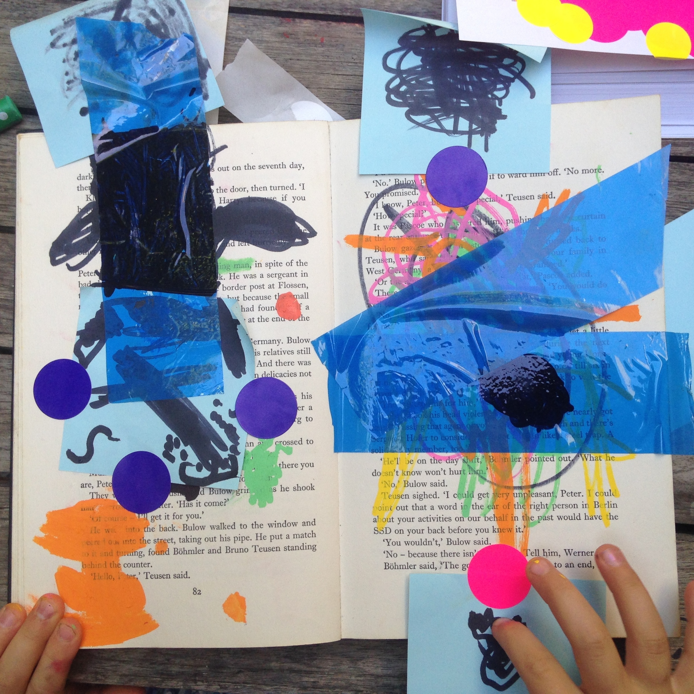 Photograph of an artwork from the ‘Kids Art Collective (Radical Library)’ event on A4’s top floor. The top down view shows a book repurposed by participants of the workshop using techniques like collage and colouring-in.
