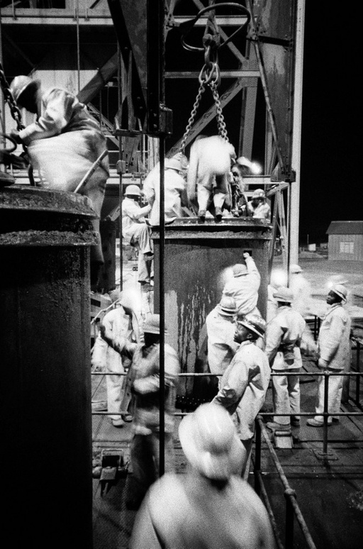 David Goldblatt’s monochrome photograph ‘Climbing into kibbles at the shaft-head, the shift gets ready to go down. President Steyn No.4 shaft, Welkom, Orange Free State. 1969’.
