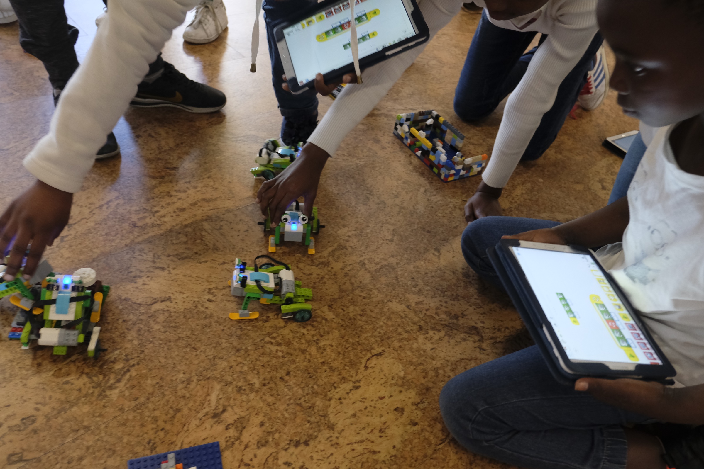 Event photograph from the Lego Robotics workshop by ORT SA CAPE on A4’s top floor shows children playing with robotic lego toys and tablet computers.
