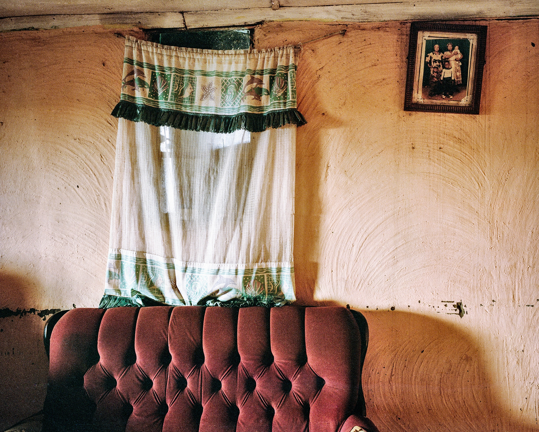 Lindokuhle Sobekwa's photograph 'Kwa Malume Mxolisi' shows a curtain covering a window and bunched at the top of a cushioned sofa.
