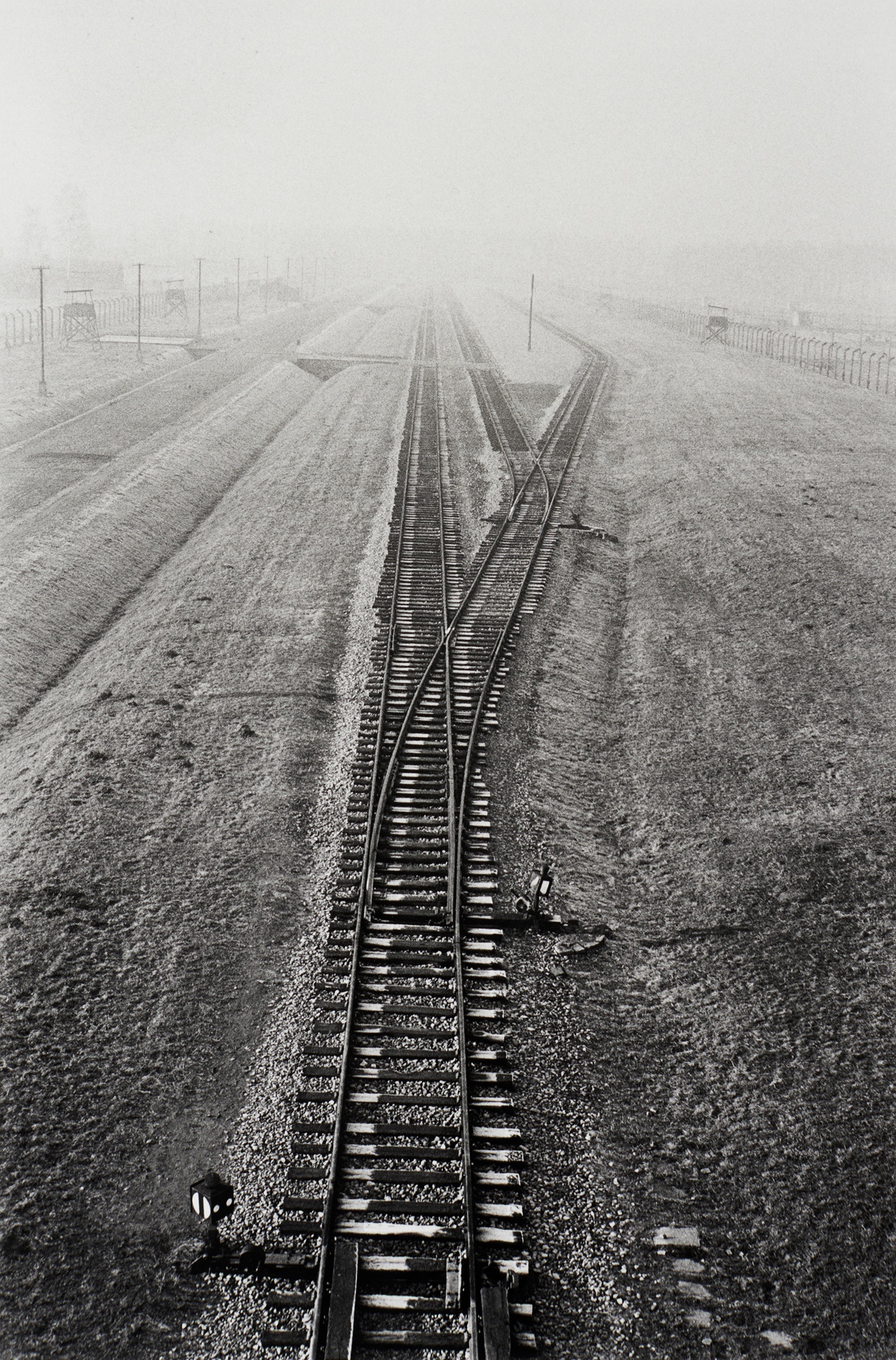 Santu Mofokeng's monochrome photographic print 'End of the Line, KZ2-Auschwitz (Landscapes of Trauma)' shows a single railway track branching into the three lanes.
