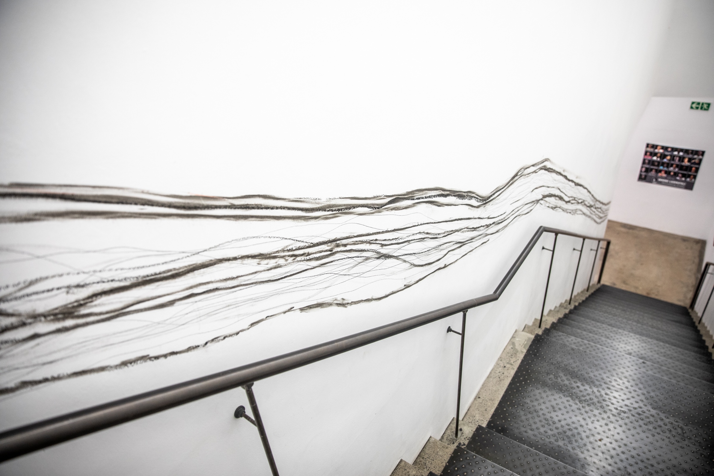 Photograph from Christian Nerf’s residency on A4’s top floor pertaining to his ‘Drawing with Obstacles’ project. On the left, multiple overlapping charcoal lines run along the wall of A4’s stairwell.
