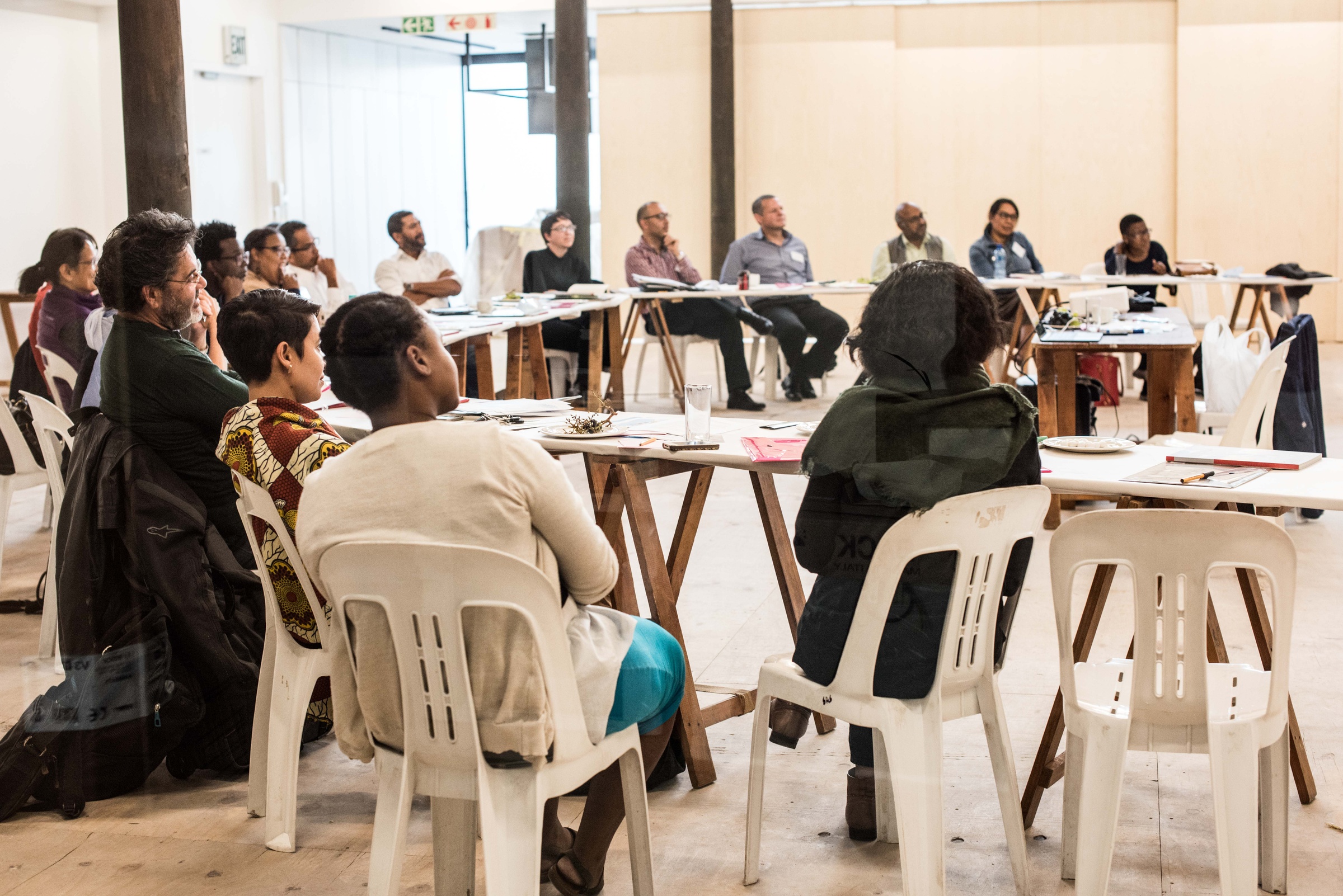 Event photograph from the ‘Integration Syndicate’ exchange hosted on A4’s top floor shows attendees seated at desks arranged in a semi-circular shape around the presenter’s desk.
