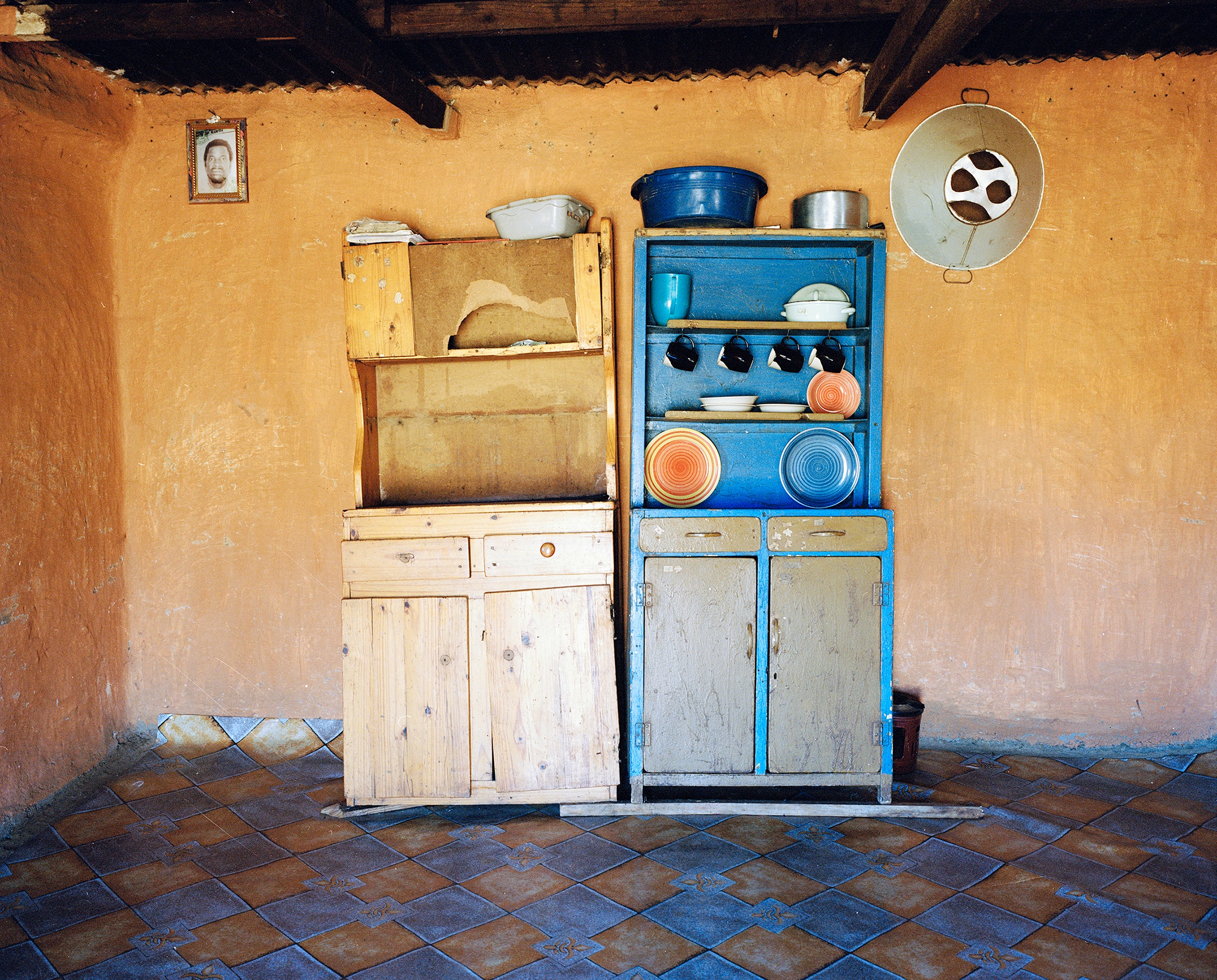 Lindokuhle Sobekwa's photograph 'Engonyama my auntie's interior' shows two wooden cabinet units standing against a wall.
