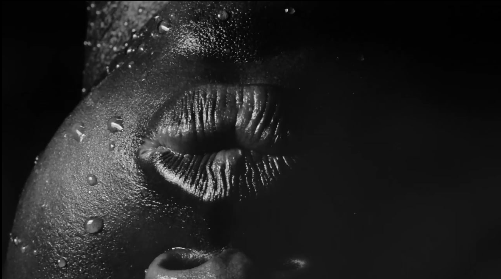 A still frame from Tony Yanick's monochrome video 'Make America Great Again (and again...and again)' depicts close-up and upside-down view of an individual's mouth.

