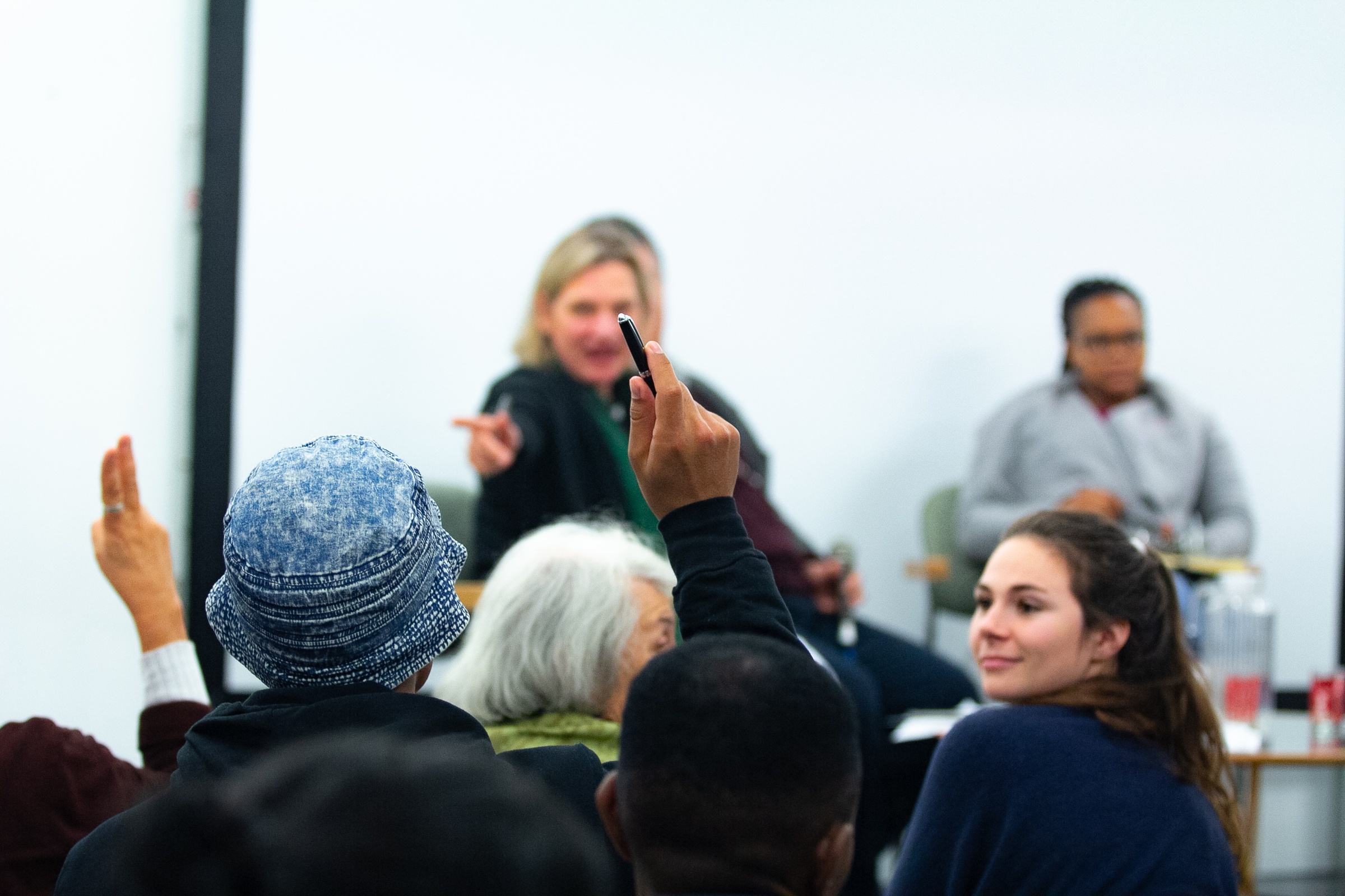 Event photograph from the 2018 rendition of the Open Book festival on A4’s ground floor. At the front, attendees with raised hands. At the back, panelists pointing at attendees for feedback.
