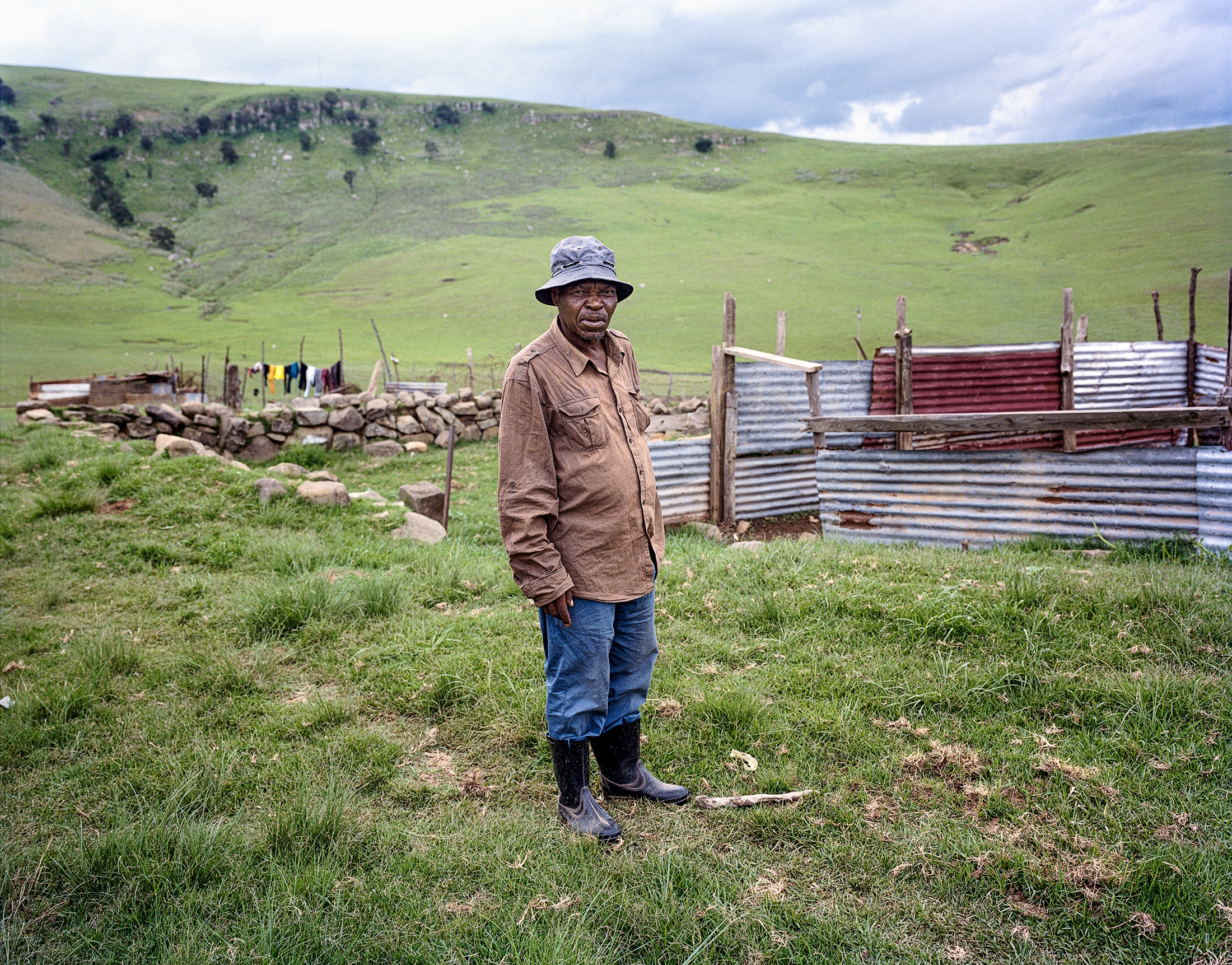 Lindokuhle Sobekwa's photograph 'Malume Stellenbosch' in a grassy plain at the front, with corrugated metal enclosure at the back.
