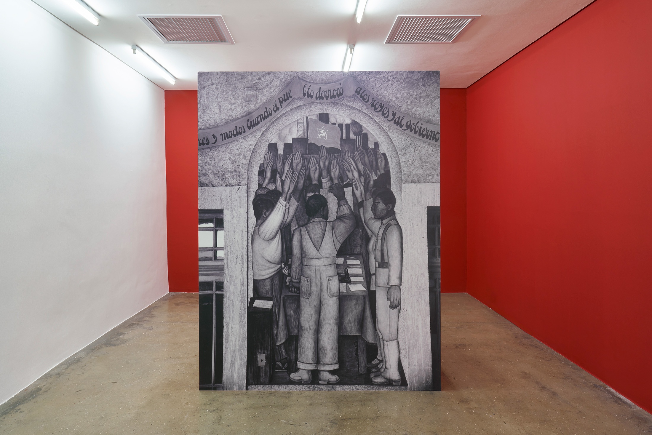Installation photograph that shows Tina Modotti's photograph 'La protesta. Corrido de la Revolución' printed as wallpaper and mounted on a freestanding MDF-board support on a concrete floor.
