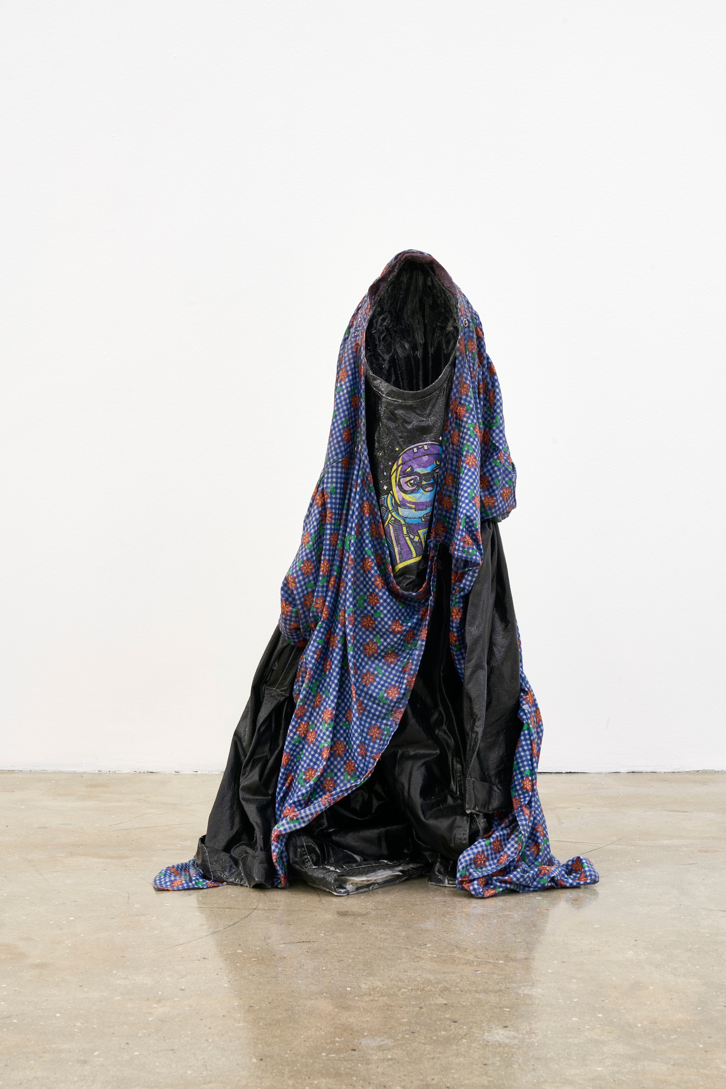 A photograph of Kevin Beasley's garment and resin sculpture 'Untitled (kid I)' standing on a concrete floor.

