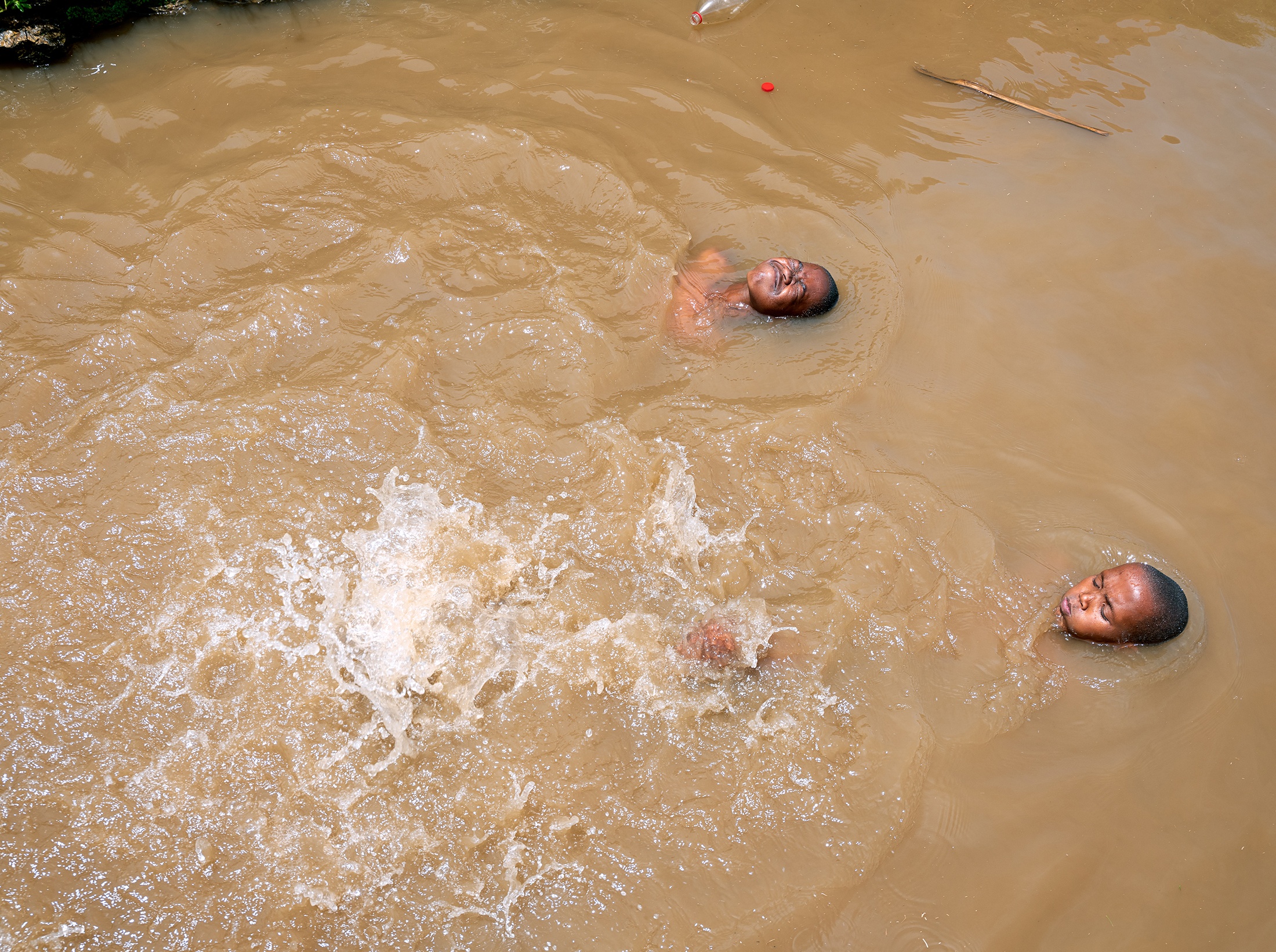 Lindokuhle Sobekwa's photograph 'Tsojana river' shows two children swimming in muddy water.
