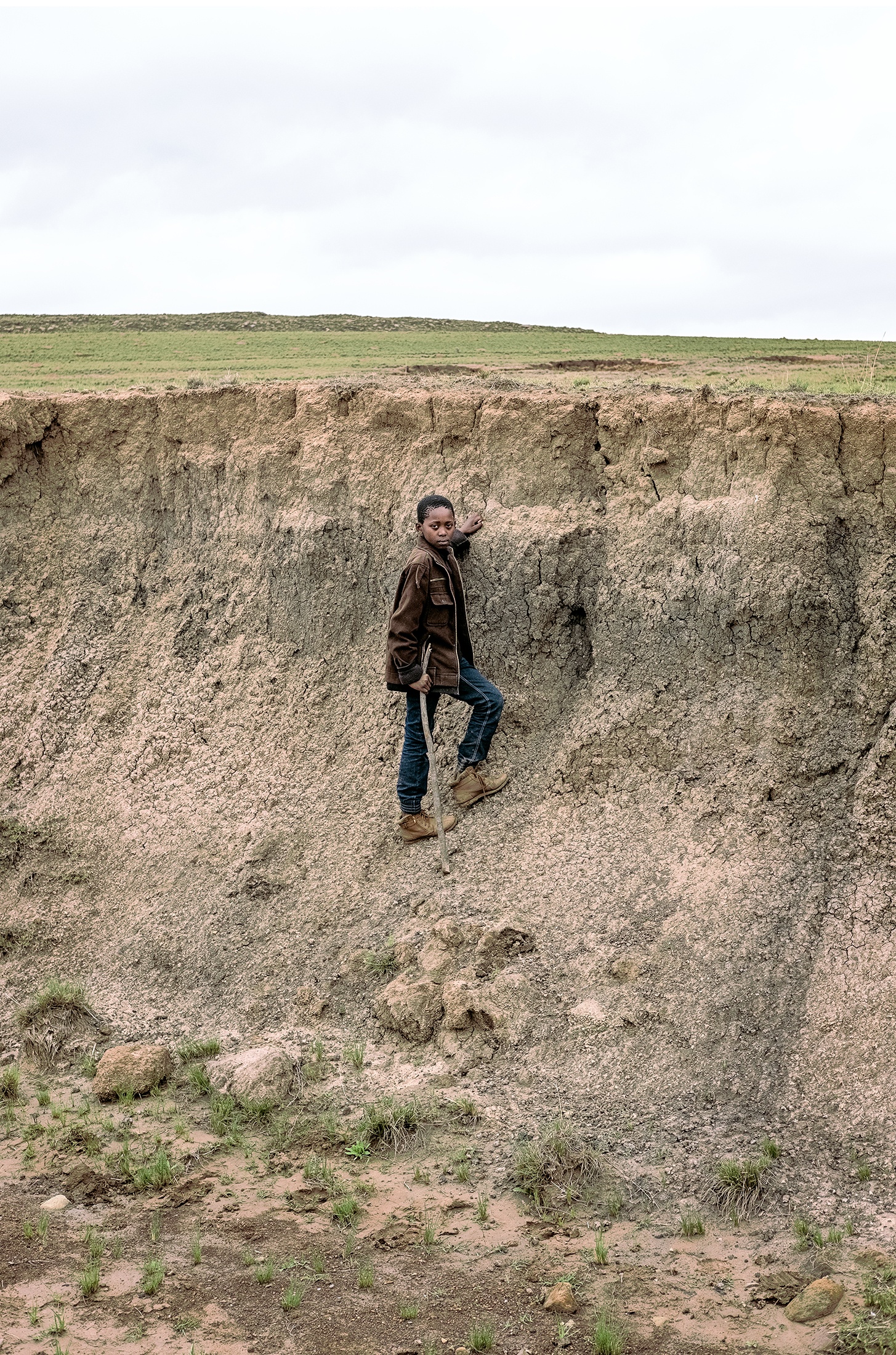 Lindokuhle Sobekwa's photograph 'uMthembu omncinci' shows a child standing on an dirt escarpment.
