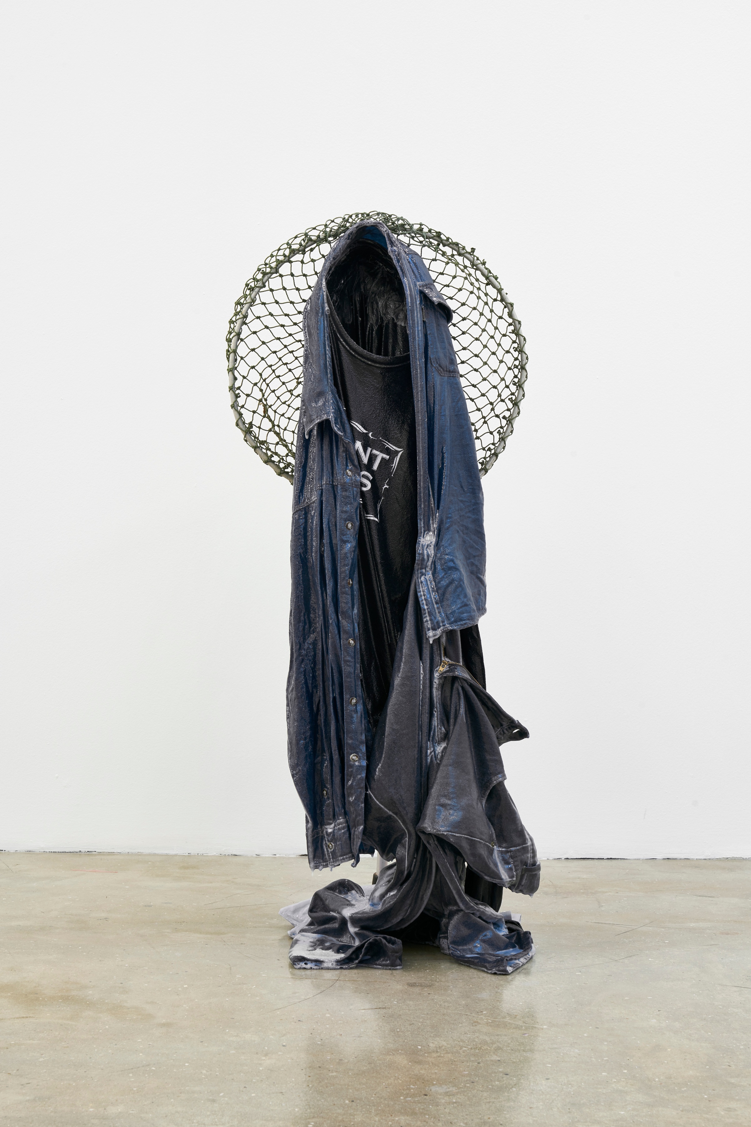 A photograph of Kevin Beasley's resin, garment and fishing net sculpture 'Fisher' standing on a concrete floor.
