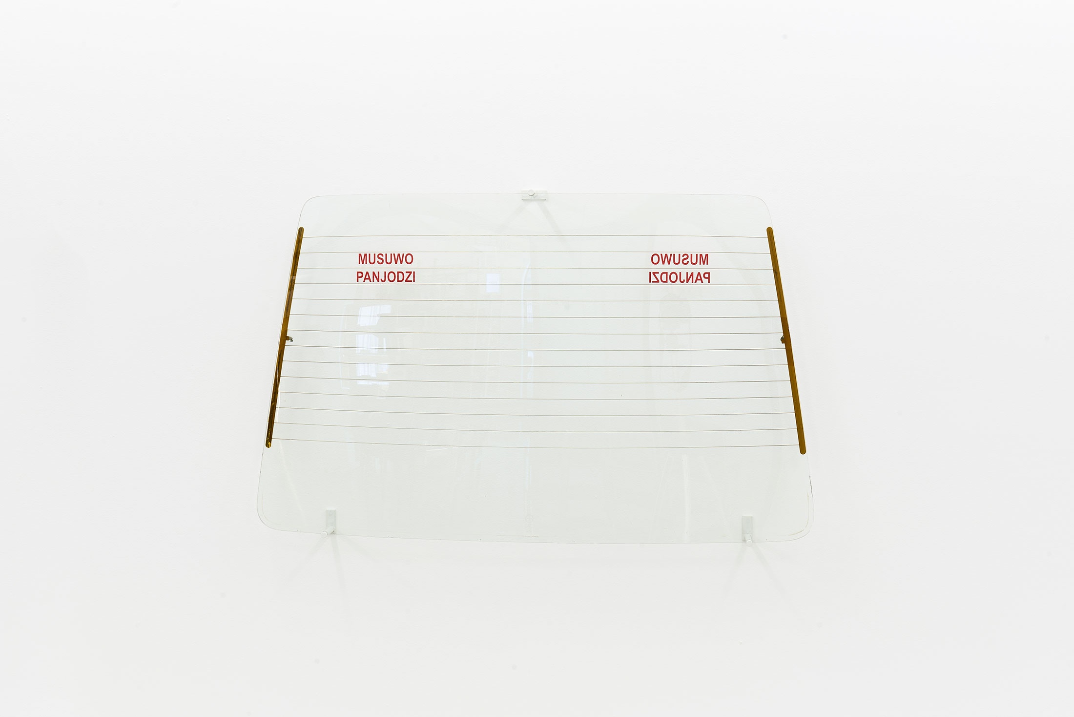 Installation photograph from the ‘Model’ exhibition in A4’s Reading Room. Xhanti Zwelendaba's salvaged taxi window 'Musuwo Panjodzi' is mounted on a white gallery wall.
