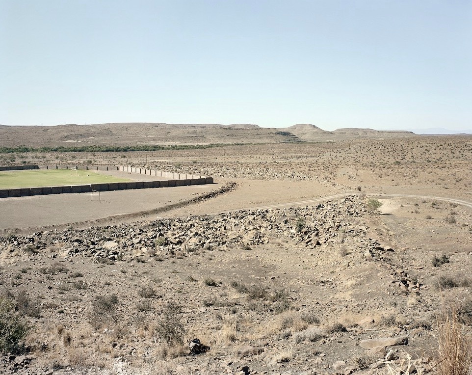 David Goldblatt's photograph 'The sports field, Merweville' shows a grassy sports filed in an arid landscape.
