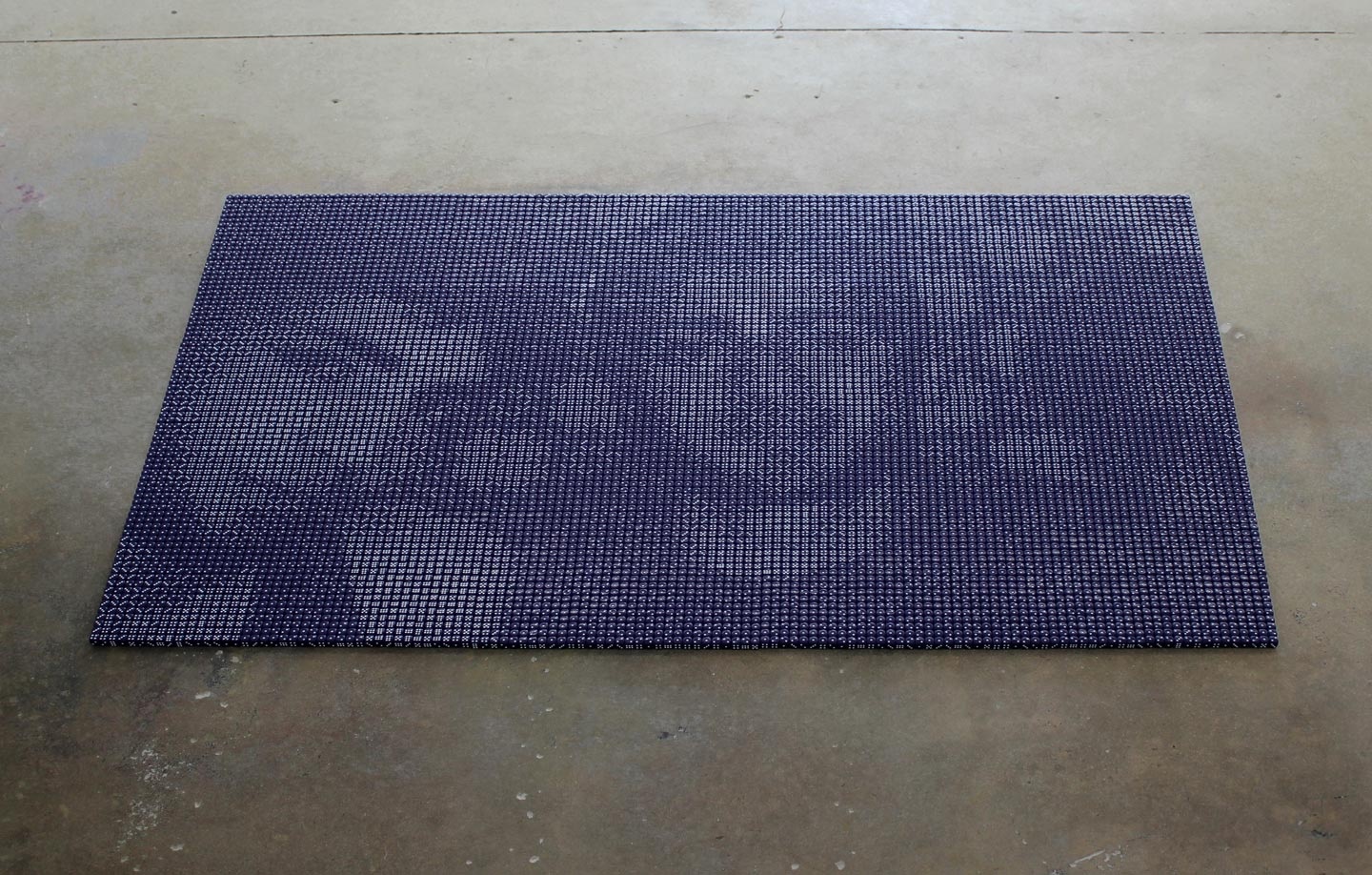 A photograph of Pierre Fouché's mixed media indigo dice sculpture 'Mahmoud & Ayaz' sitting on a concrete floor.
