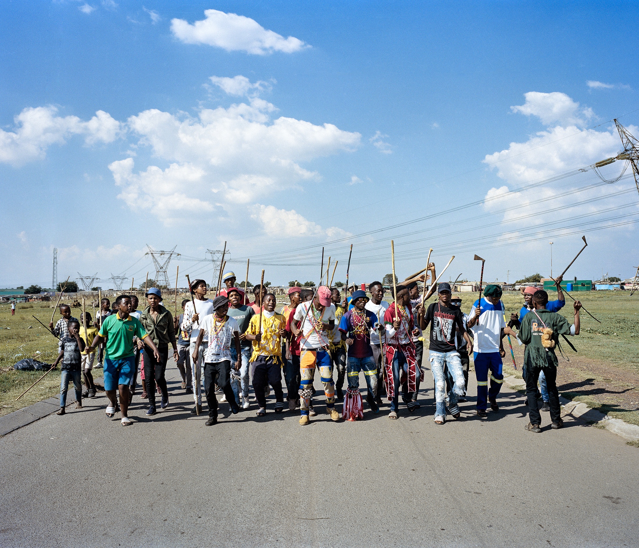 Lindokuhle Sobekwa's photograph 'Amakhwenkwe' depicts individuals marching on a tarred road.
