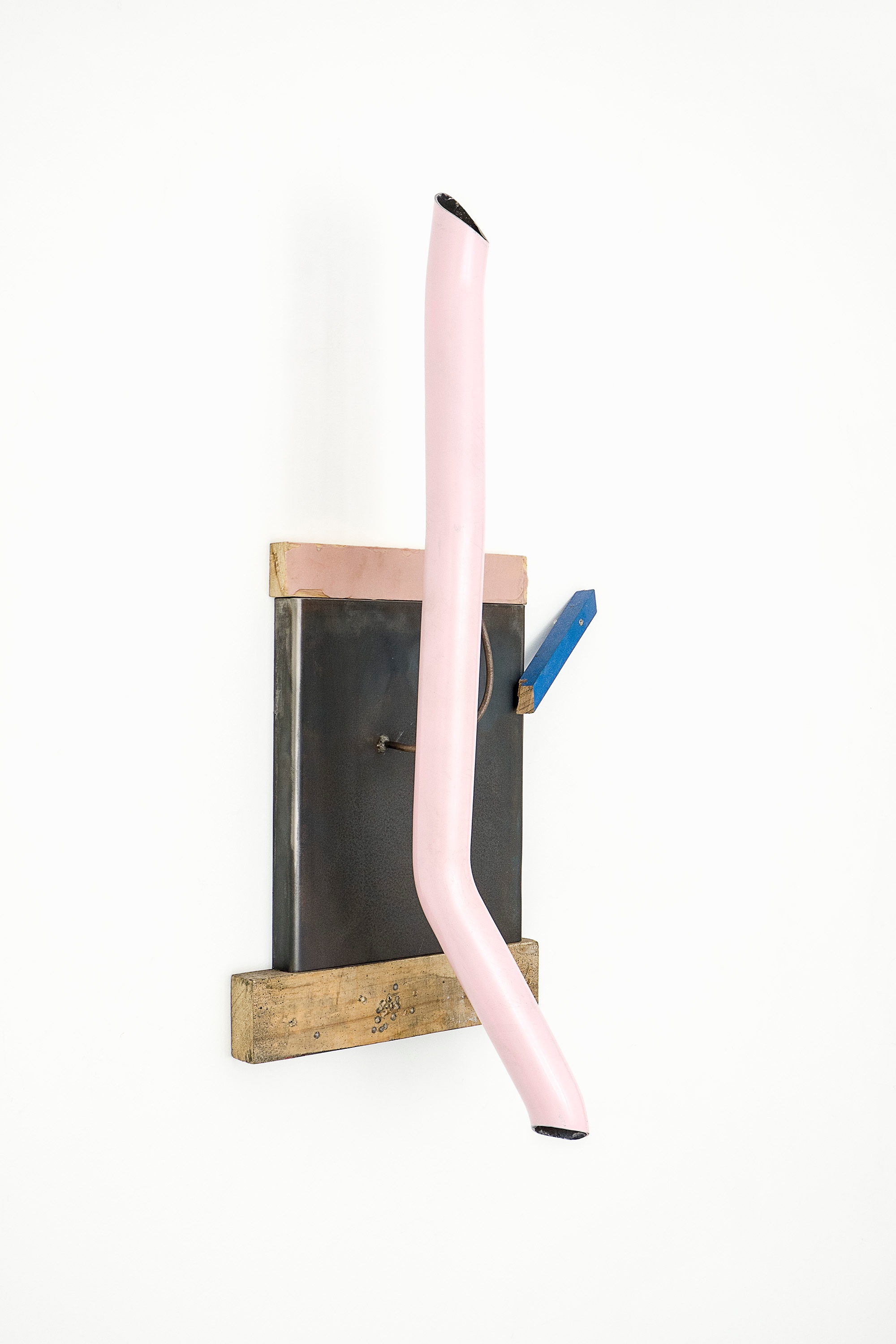 A photograph of Kyle Morland's steel, enamel, timber and industrial paint assemblage 'Just BCOZ' mounted on a white wall.
