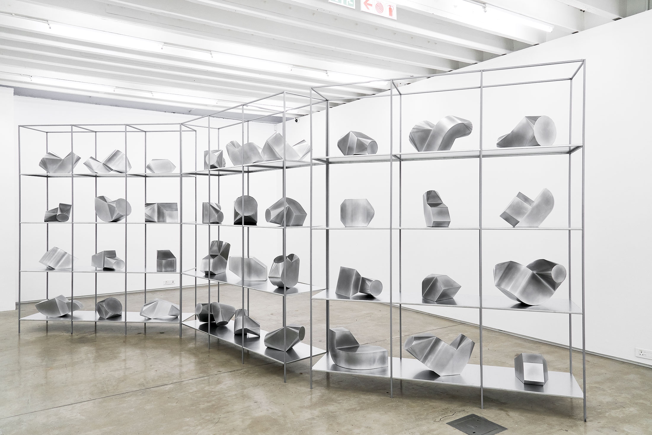Installation photograph from the 2018 rendition of ‘Parallel Play’ in A4’s Gallery that shows three aluminium shelves with aluminium sculptural forms.
