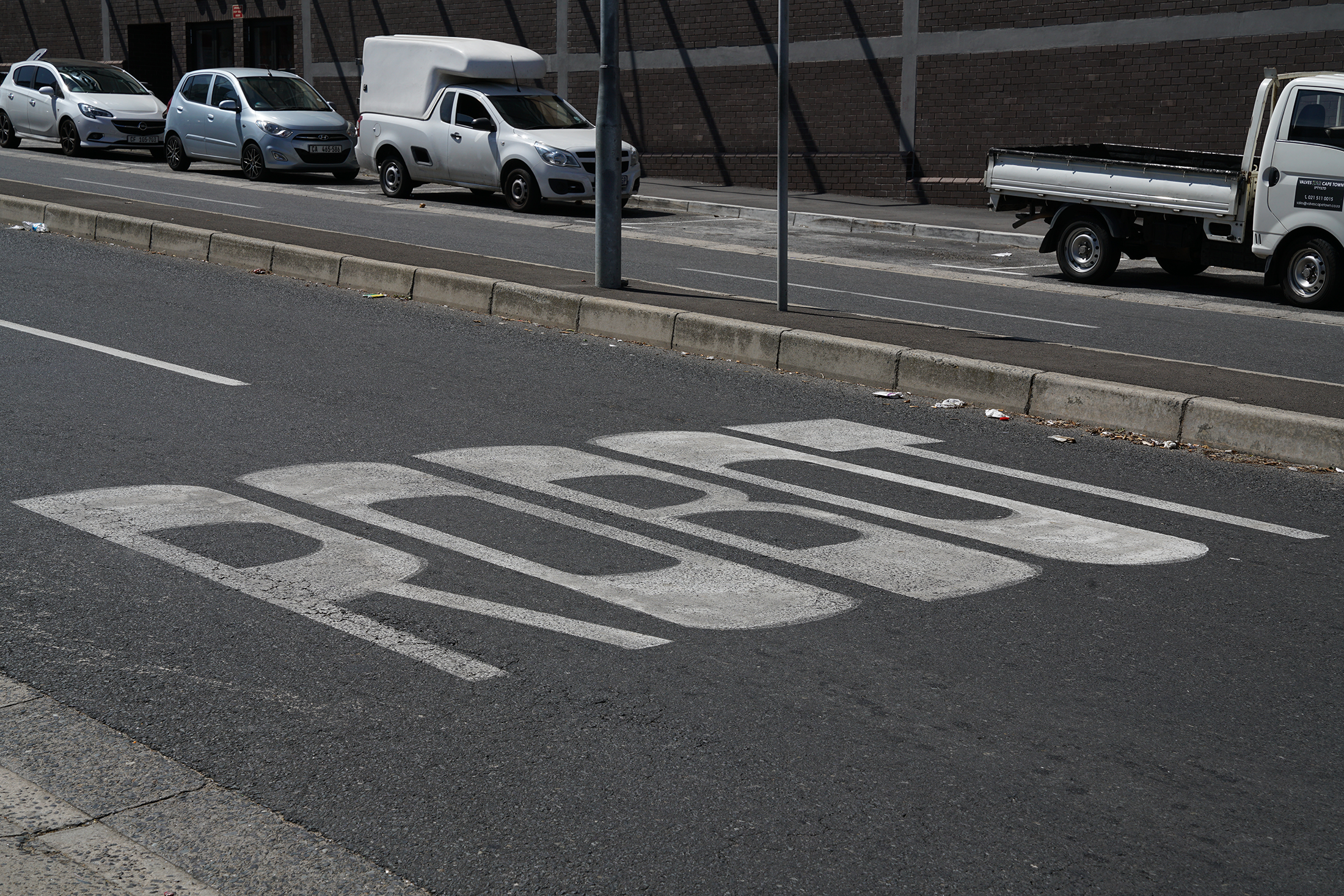 Kevin Beasley's photographic print 'Robot' depicts the word "ROBOT" described in white paint on a tarred road.
