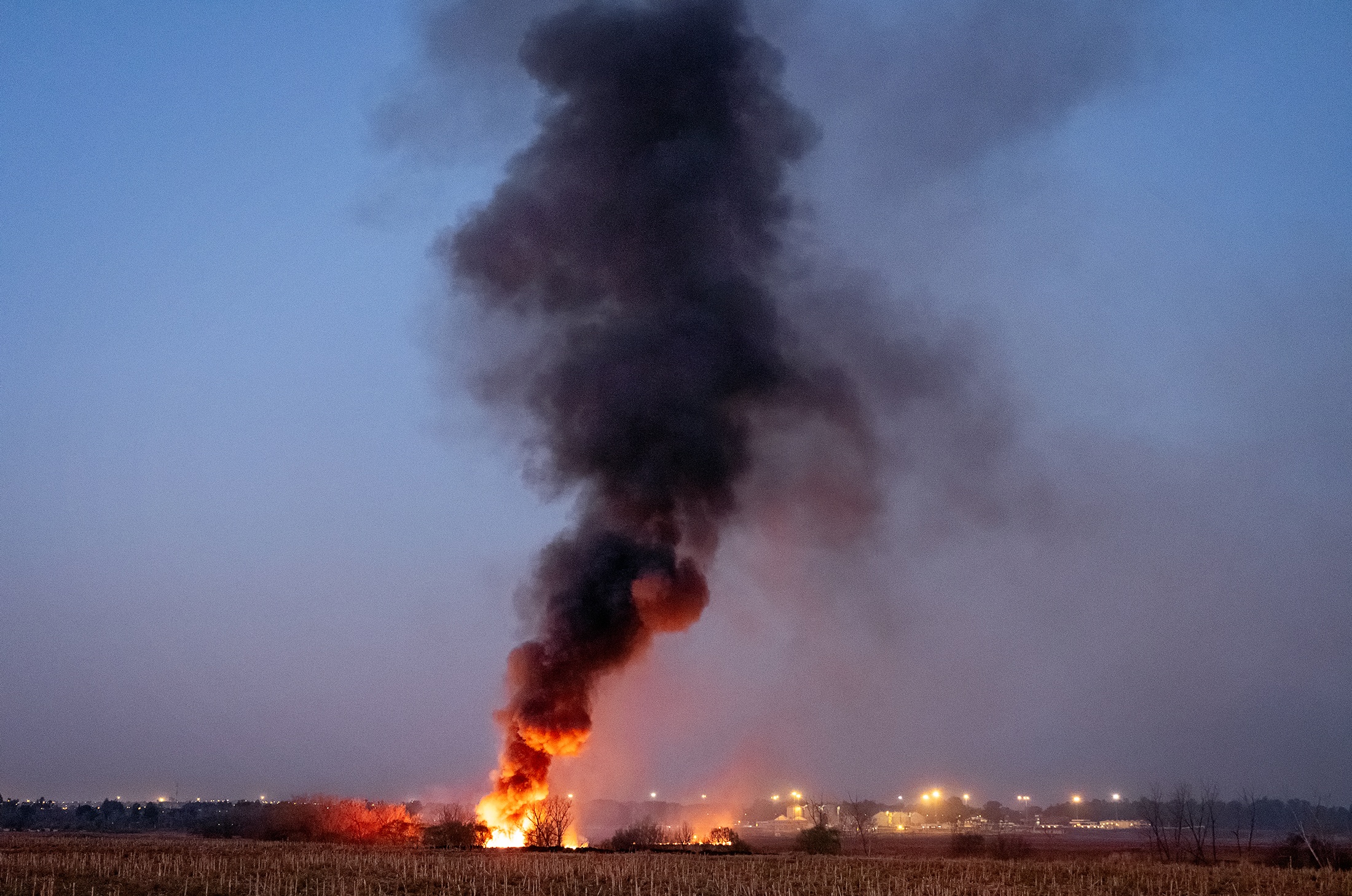 Lindokuhle Sobekwa's photograph 'Veld fire' shows a fire in a grassy plain producing a column of smoke.
