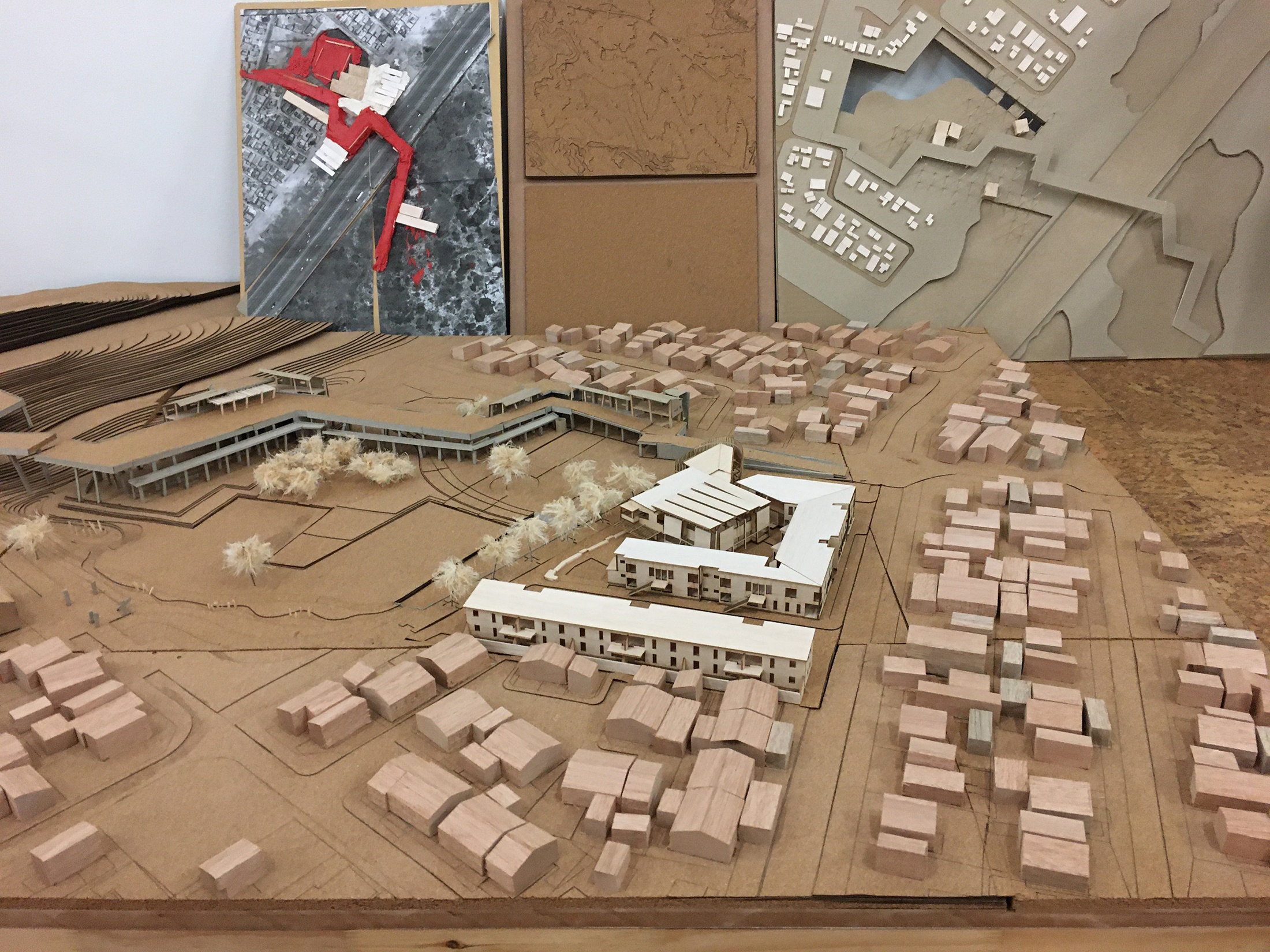 Photograph of an artwork from the Masters of Architecture Graduate Exhibition on A4’s top floor that consists of a cardboard model that depicts topography and buildings.
