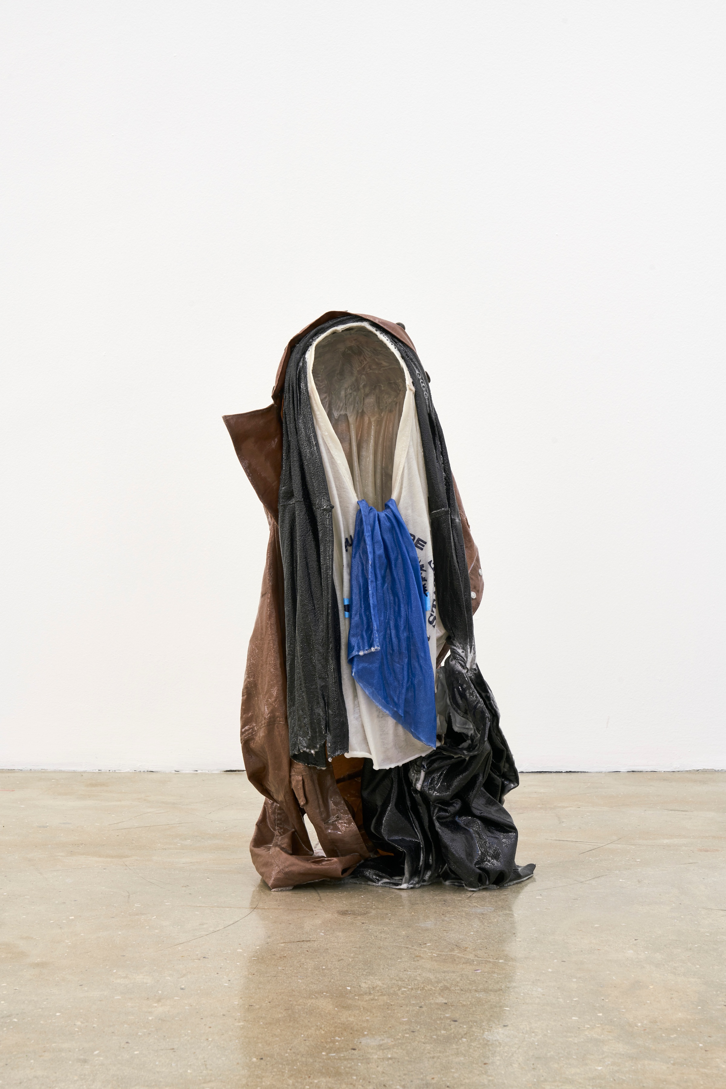 A photograph of Kevin Beasley's garment and resin sculpture 'Untitled (kid II)' sitting on a concrete floor.
