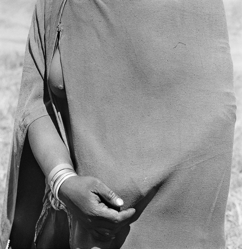 David Goldblatt's monochrome photograph 'Woman Going To The Trading Store Holding Money Under Her Blanket, Flagstaff, Transkei' shows an individual's torso partially covered with fabric.
