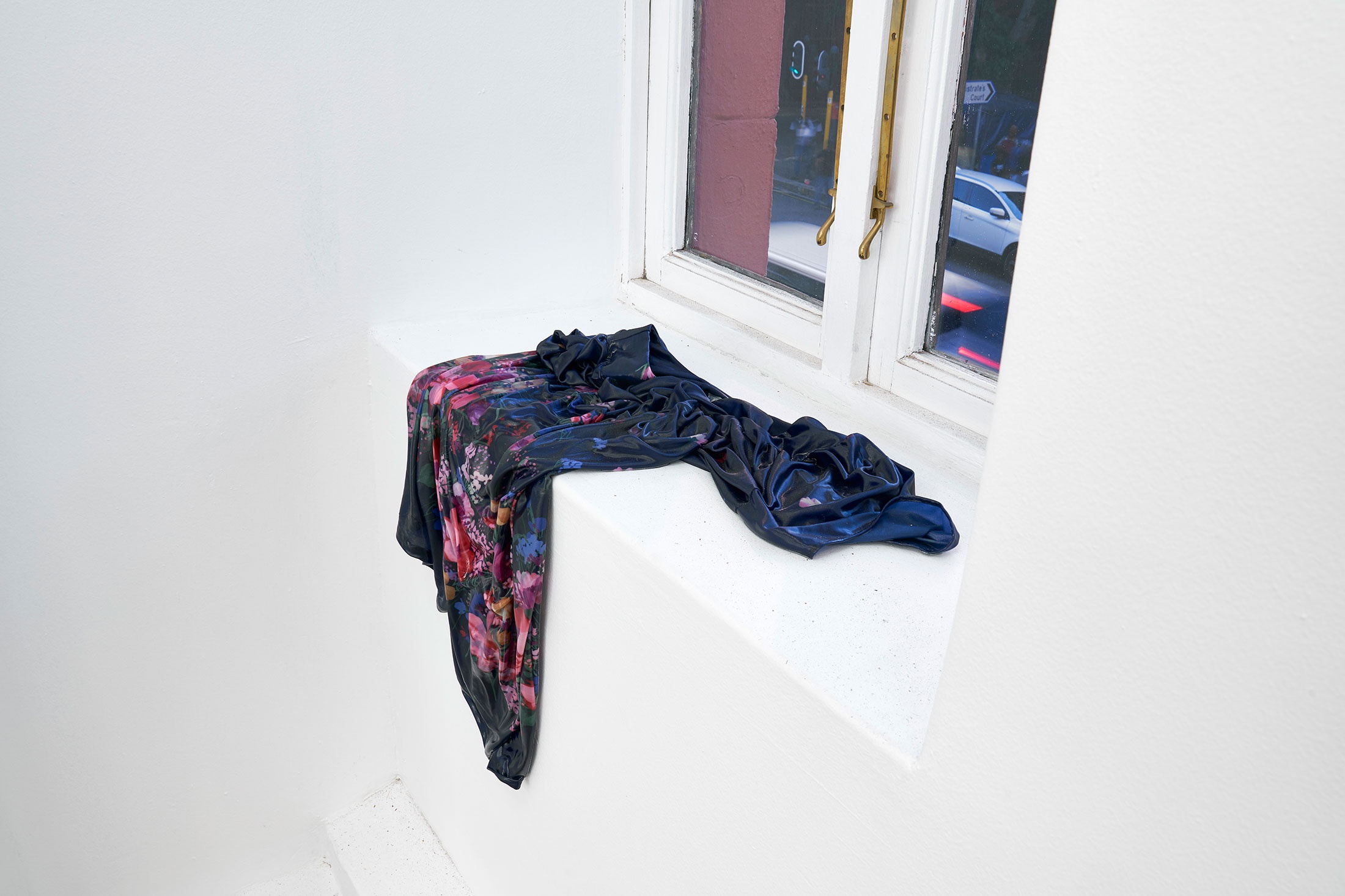 A photograph of Kevin Beasley's untitled housedress and resin sculpture sitting on a white windowsill.
