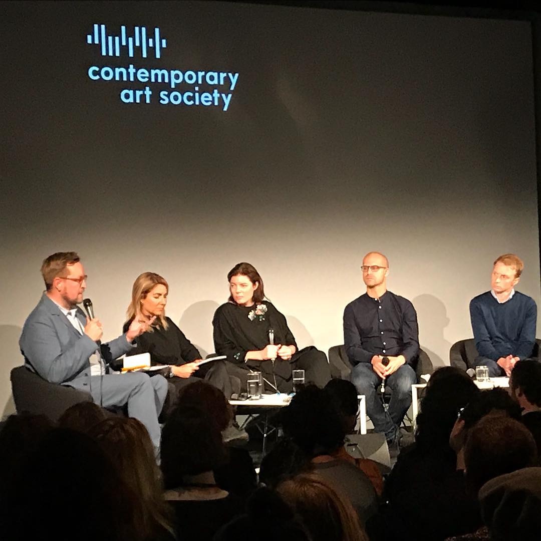 Event photograph from the Contemporary Art Society Curatorial Summit ‘Private in the Public Realm: Towards new Alliances’ at Frieze, London shows five contributors seated in front of a wall. From the lefthand side: Ossian Ward, Katerina Gregor, Antonia Carver, Josh Ginsburg and Nick Thornton.
