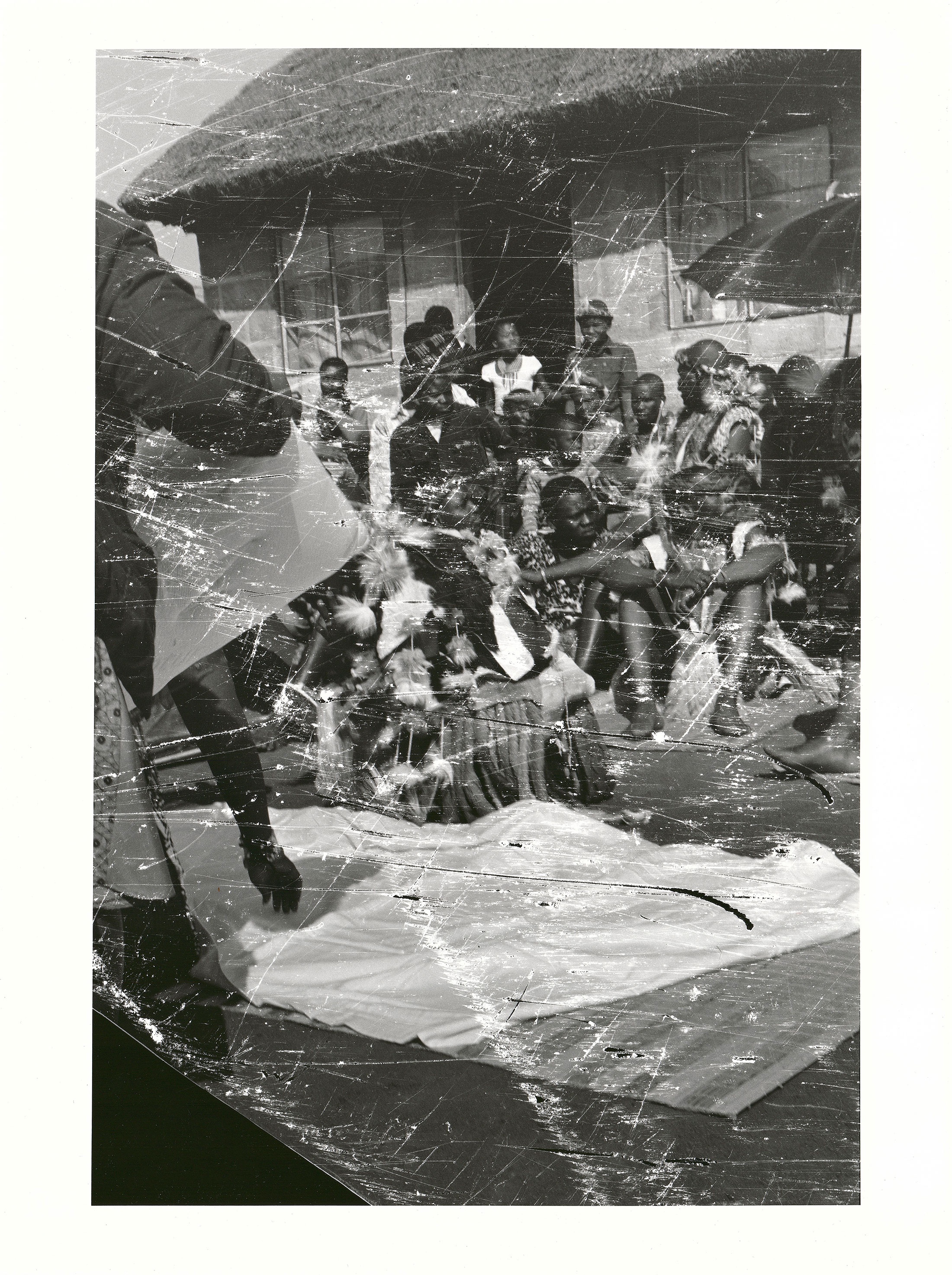 Sabelo Mlangeni’s ‘Ukugiyela izinkomo, Umabo, Umkhwenyane umashidini amhlophe’, a black and white photograph depicting wedding attendees seated outside a thatched building.
