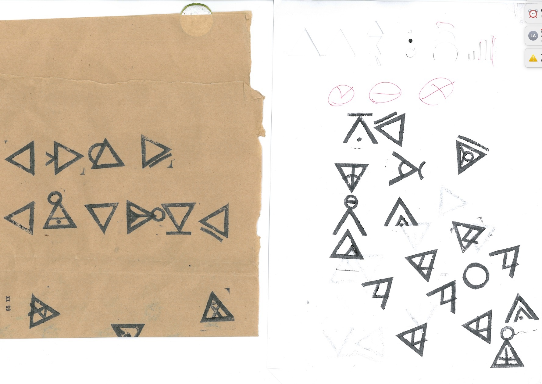 Process image from the offsite development of the online ‘IsiBheqe keyboard’ by linguist Pule kaJanolintji. A digital photograph used as a computer background shows characters from the IsiBheqe script printed on a sheet of brown paper on the left, and a sheet of white paper on the right.
