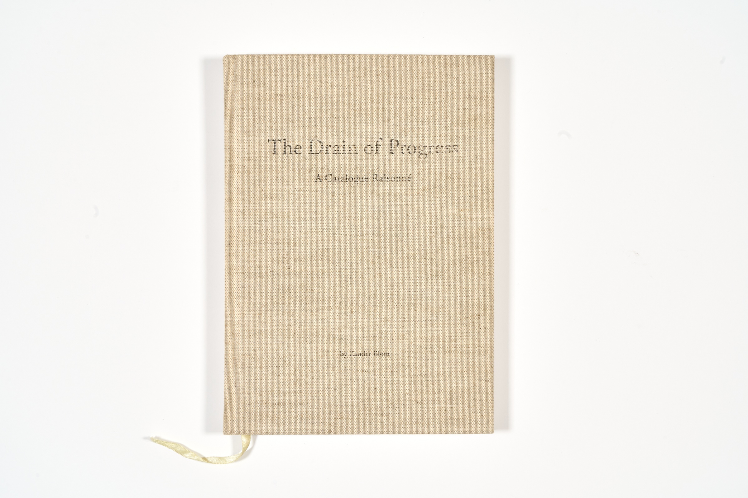 A topdown photograph of the cover of Zander Blom's photo-book 'The Drain of Progress: A Catalogue of Raisonné' on a white background.
